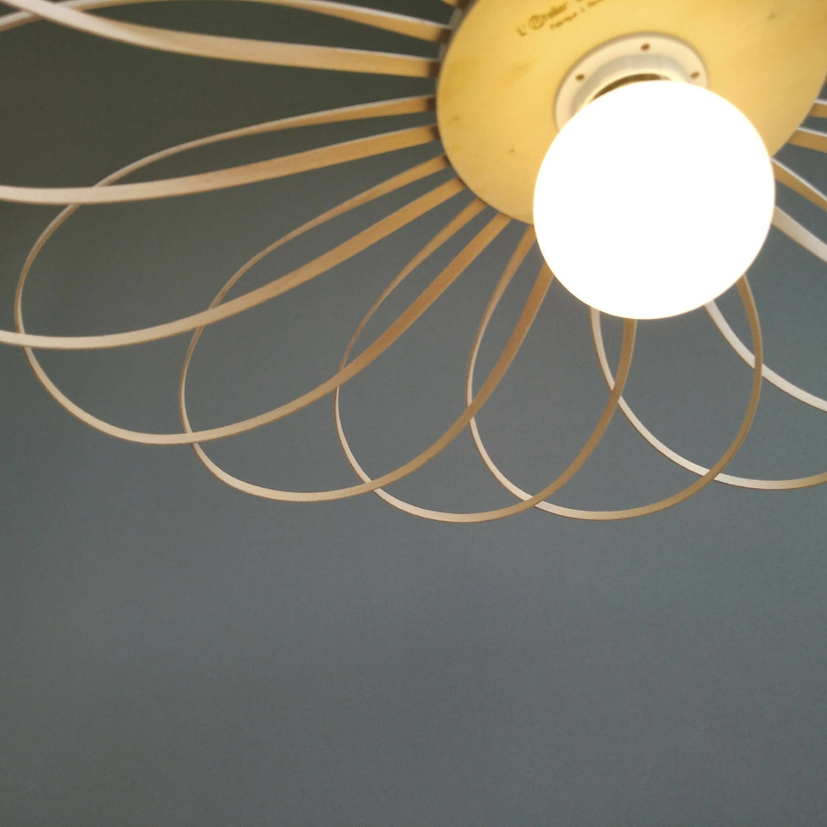 Suspension fleur : gros plan sur disque jaune et fils métalliques beige avec ampoule blanche.