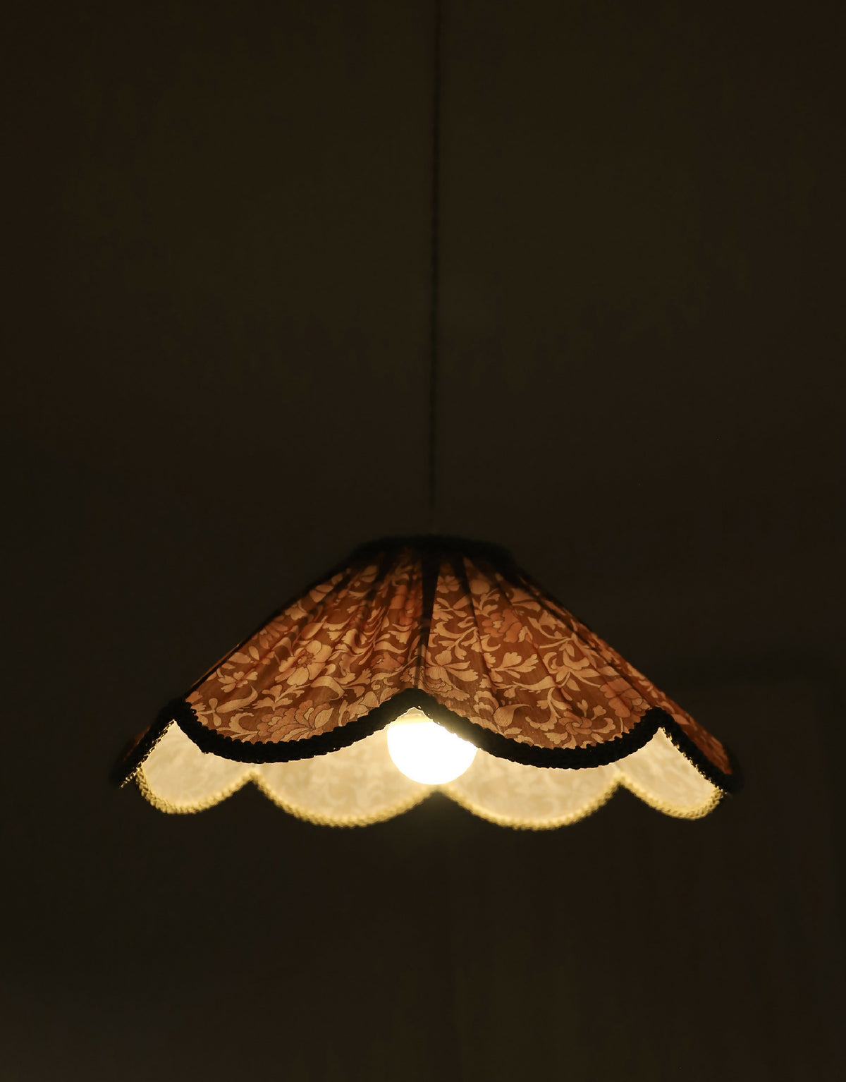 Suspension florale en tissu orange, abat-jour en forme arrondie avec bord clair.