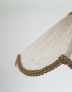Détail de l’abat-jour beige : tissu texturé et bord ondulé tressé