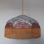 Suspension rétro avec abat-jour arrondi gris, motifs japonais et franges dorées.