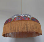 Suspension rétro : abat-jour rond gris à motifs, intérieur rouge et franges dorées.