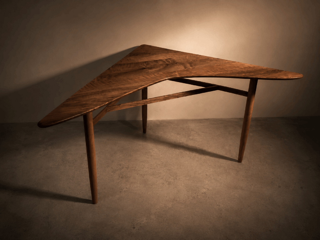 Table d’angle en bois brun, plateau trapézoïdal, pieds fuselés.