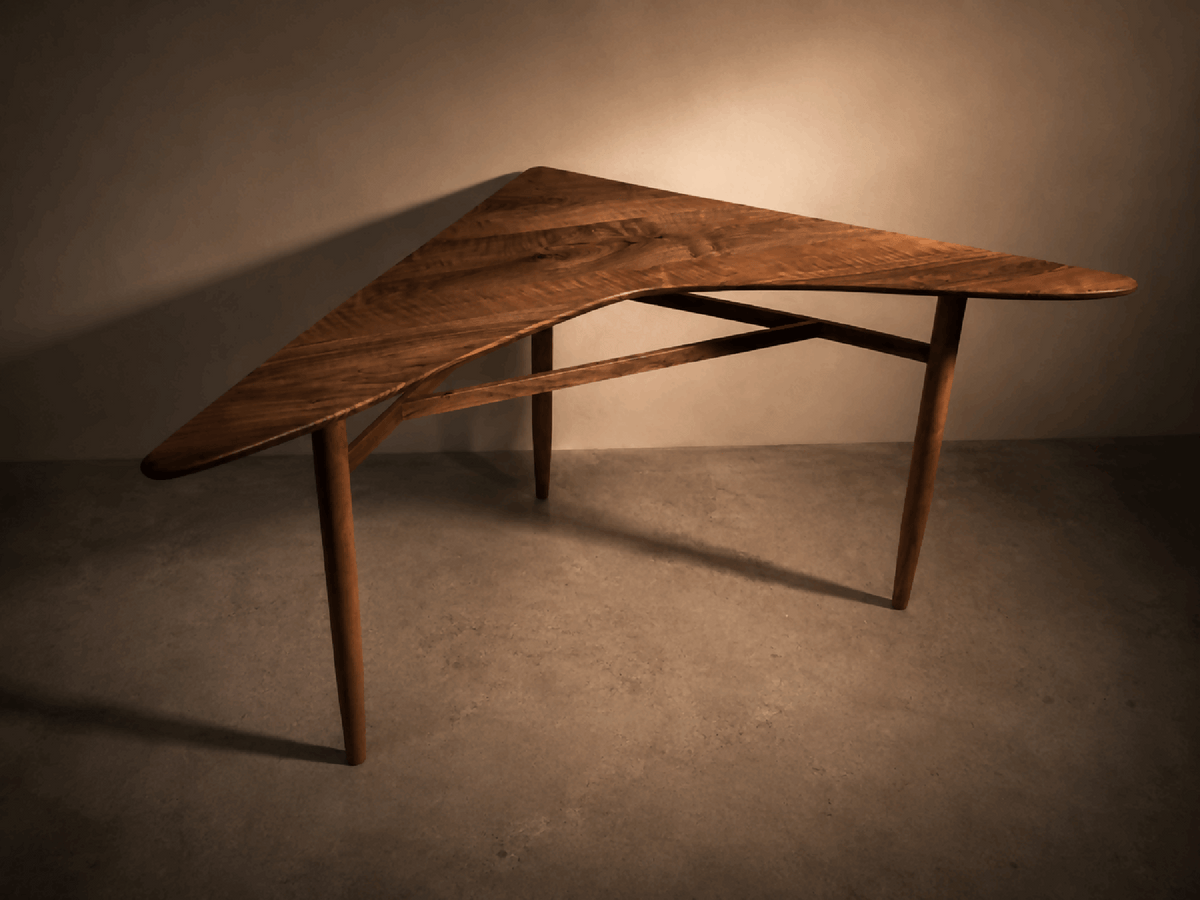 Table d’angle en bois brun, plateau trapézoïdal, pieds fuselés.