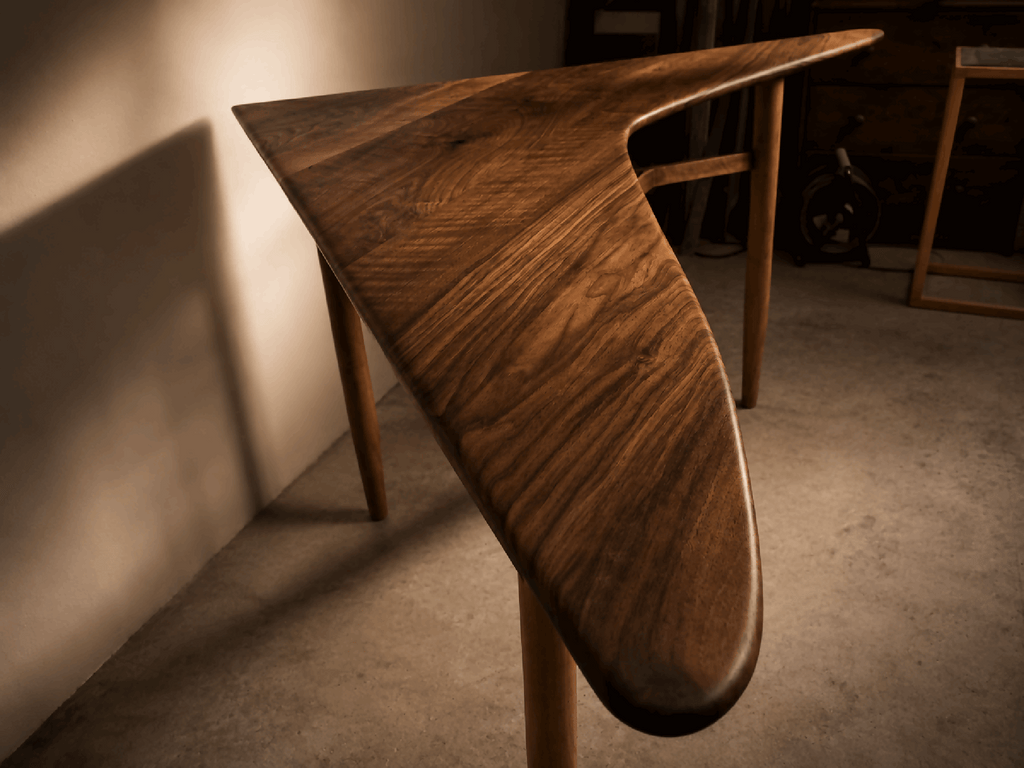 Table d’angle en bois brun, bord arrondi du piètement, pieds en bois.