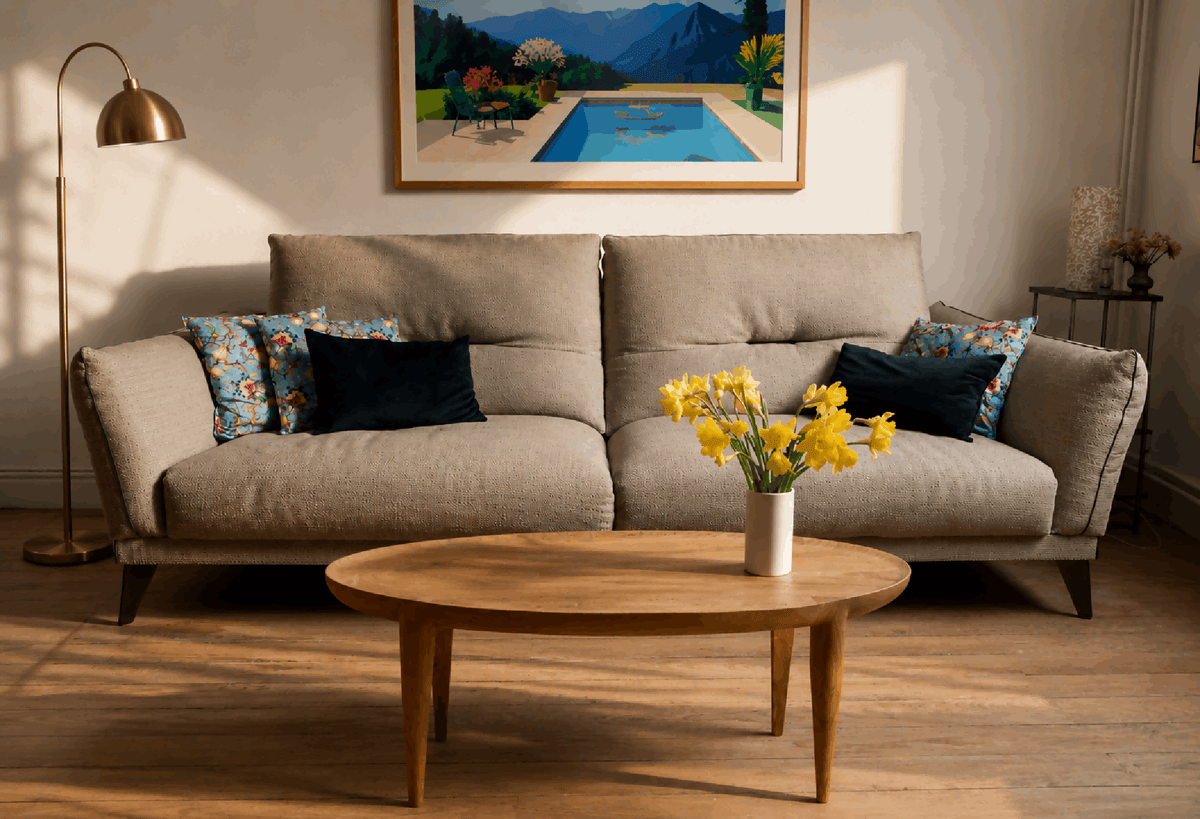 Table basse ronde en bois clair, pieds fins, plateau avec veines apparentes.