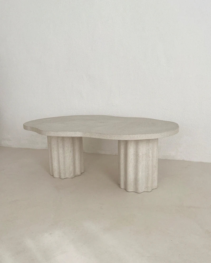 Table basse HESTIA ronde, plateau clair texturé et quatre pieds cylindriques cannelés.
