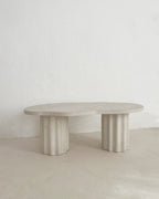 Table basse HESTIA à plateau rond clair et pieds cylindriques cannelés, vue de face.