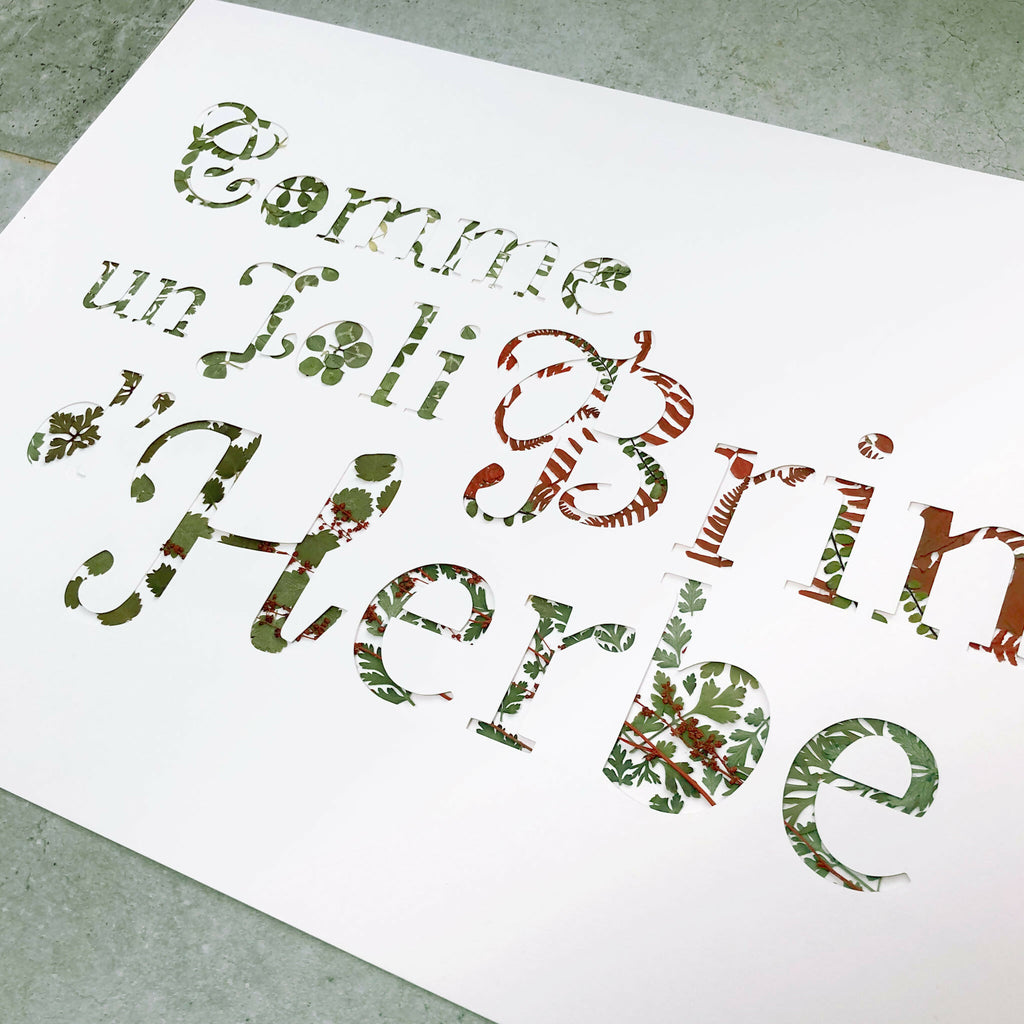 Tableau A3 posé au sol, lettres en collage de plantes séchées vertes et brunes
