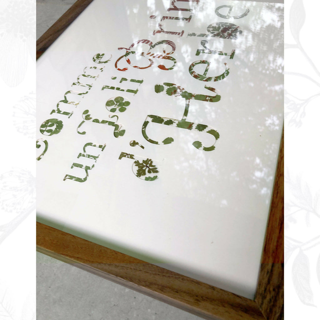 Tableau A3 en papier blanc, lettres découpées en plantes séchées vertes et brunes