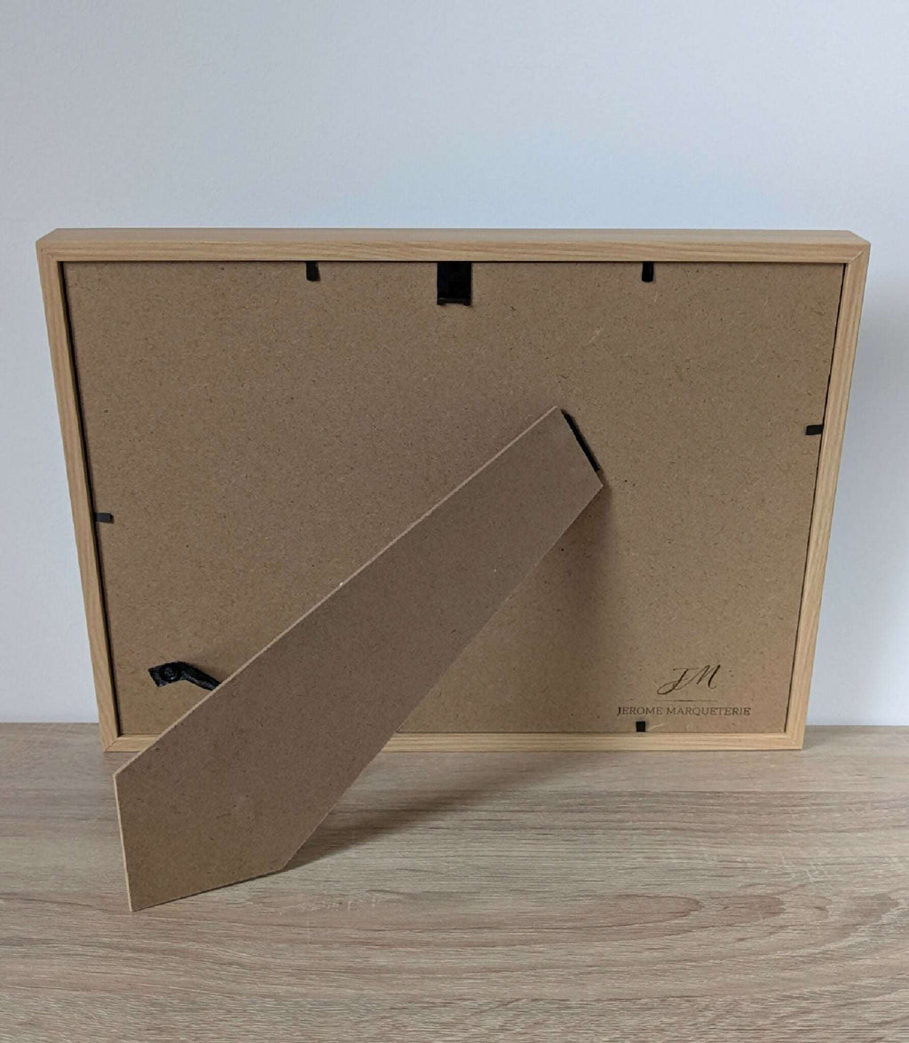 Dos du tableau encadré en bois clair avec accroche et étiquette de fabricant.