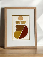 Tableau abstrait encadré en bois clair, illustration dorée et rouge, vue en biais.