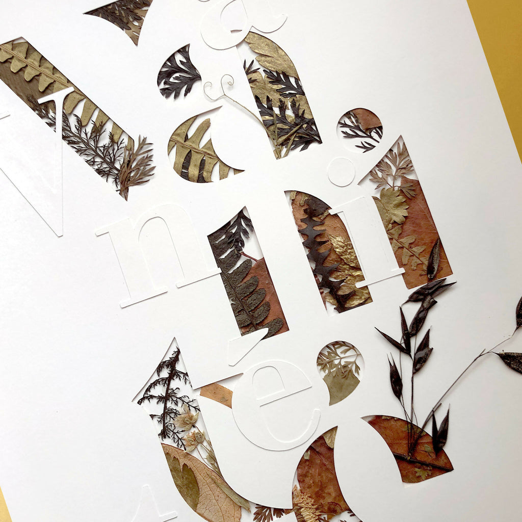 Tableau A3 en collage de plantes séchées formant des lettres, sur fond clair