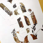 Tableau A3 en collage de plantes séchées formant des lettres, sur fond clair