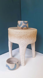 Tabouret en céramique beige texturé avec bol en céramique bleu sur le dessus
