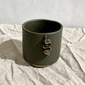 Tasse à café vert foncé avec motif doré sur le devant.