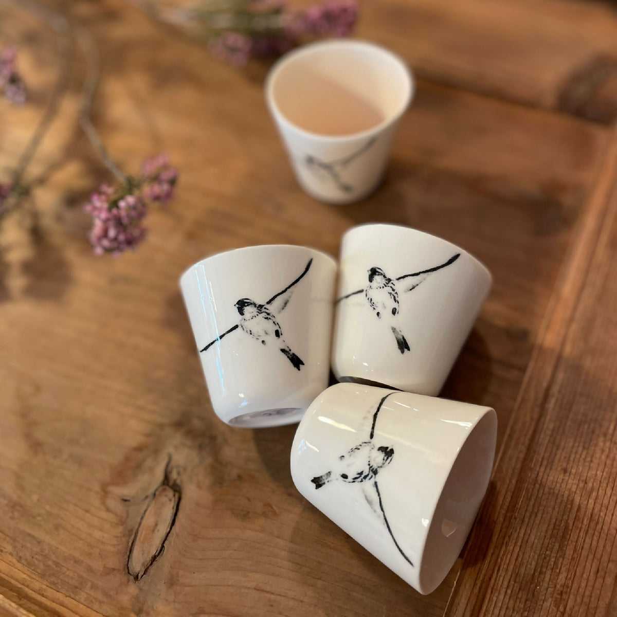 Lot de tasses à ristretto blanches avec dessins d’oiseaux noirs, tasses disposées sur le bois