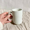 Tasse à thé blanche en céramique, anse sculptée avec reliefs.