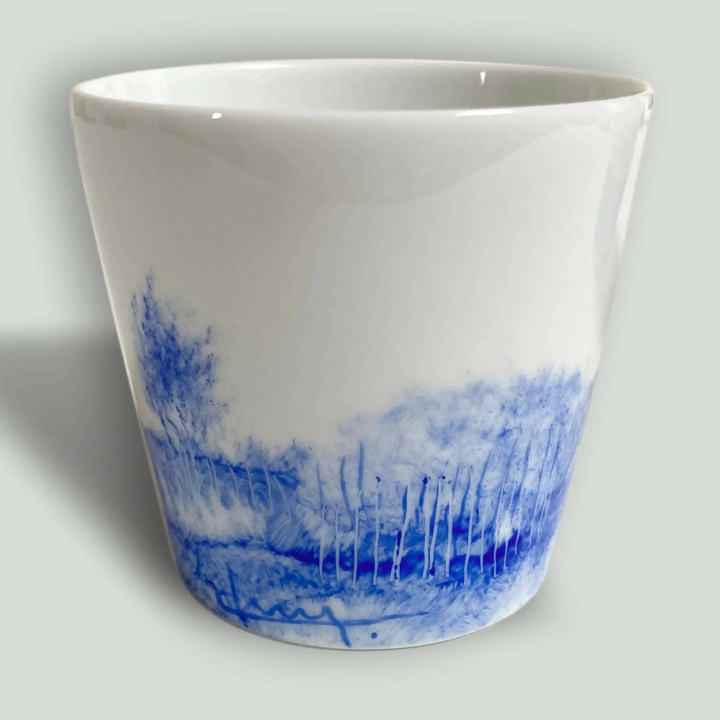 Tasse en porcelaine blanche avec motif paysage bleu sur la paroi