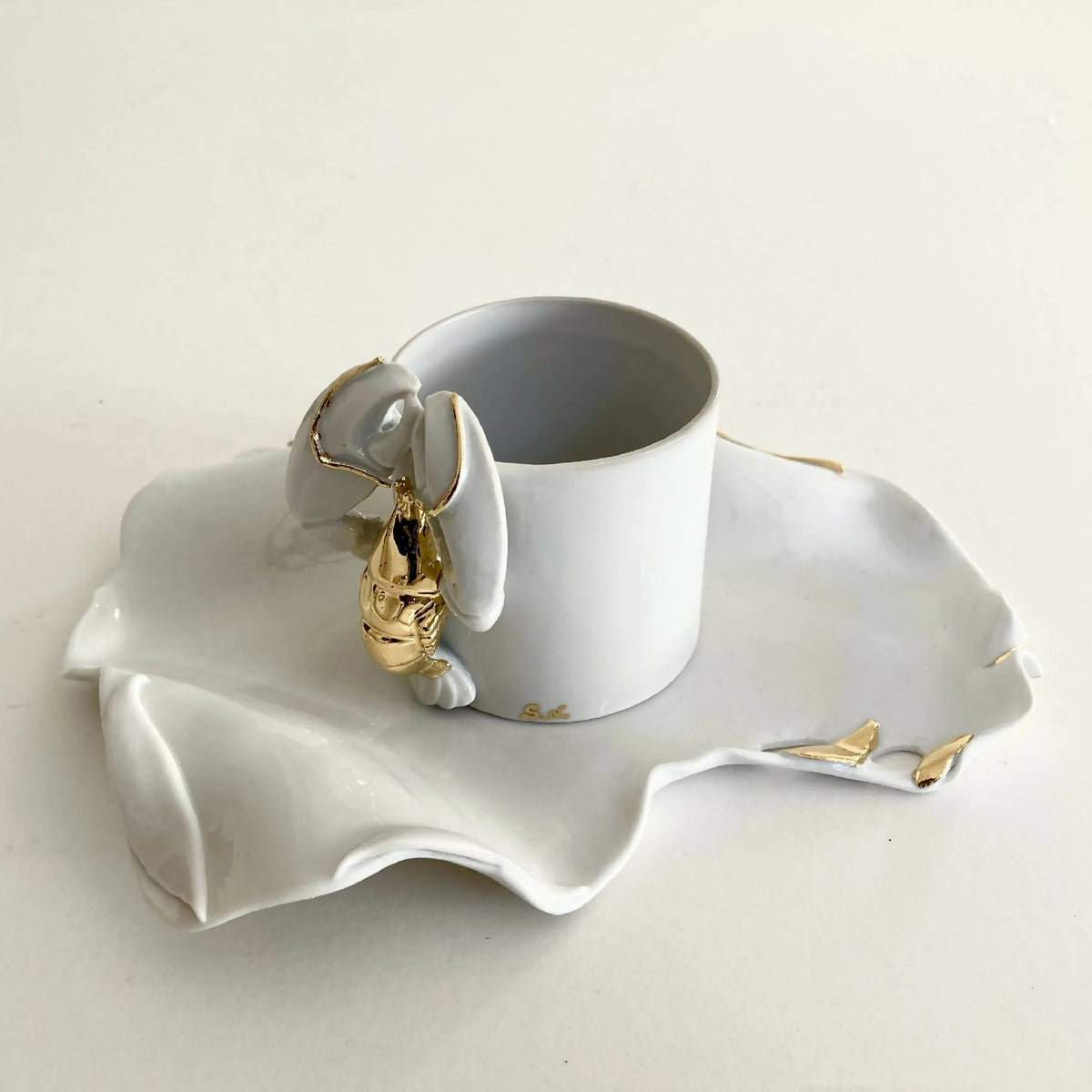 Tasse blanche avec soucoupe homard et éclats dorés sur les contours.