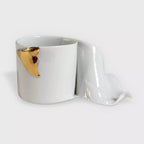 Tasse blanche avec accent ruban doré, soucoupe assortie sculptée, ensemble coordonné.