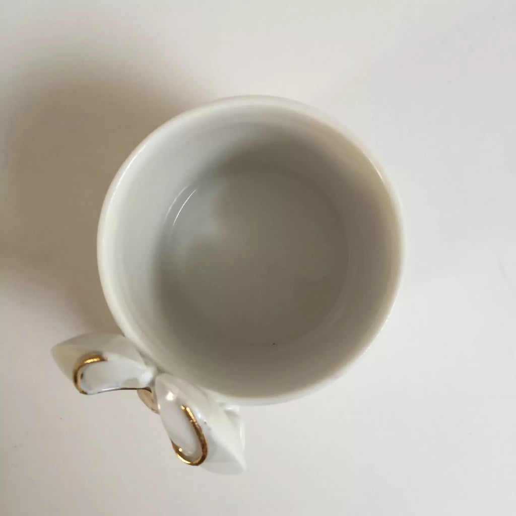 Tasse blanche à figurine de homard doré, vue de l’intérieur et de l’anse