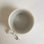 Tasse blanche à figurine de homard doré, vue de l’intérieur et de l’anse