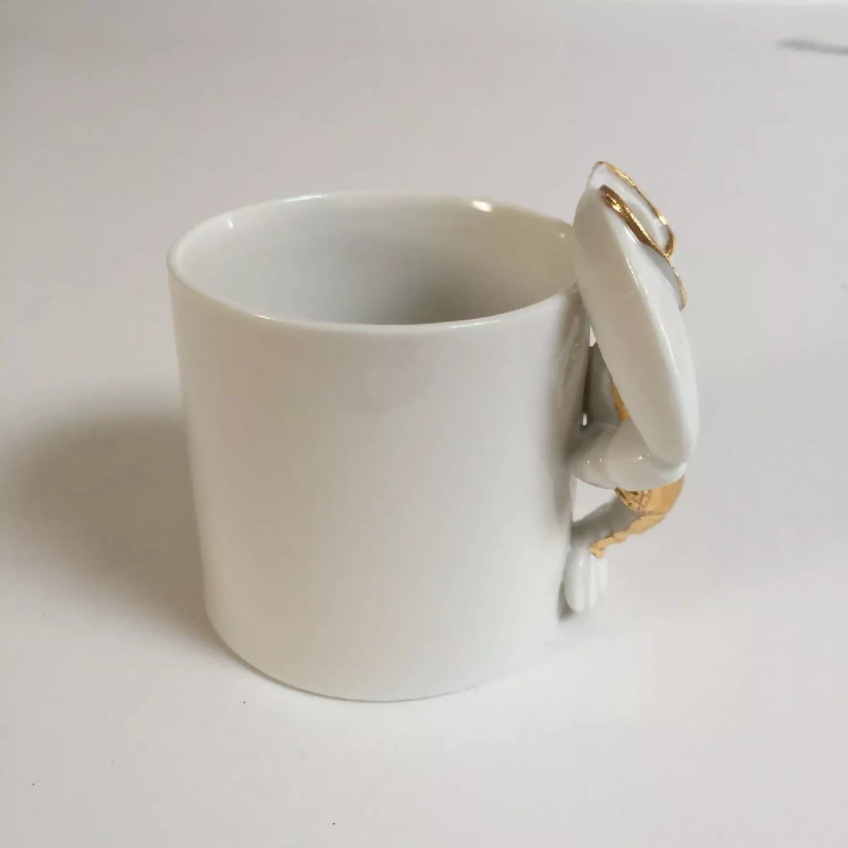 Tasse blanche avec figurine de homard doré sur le côté et l’anse