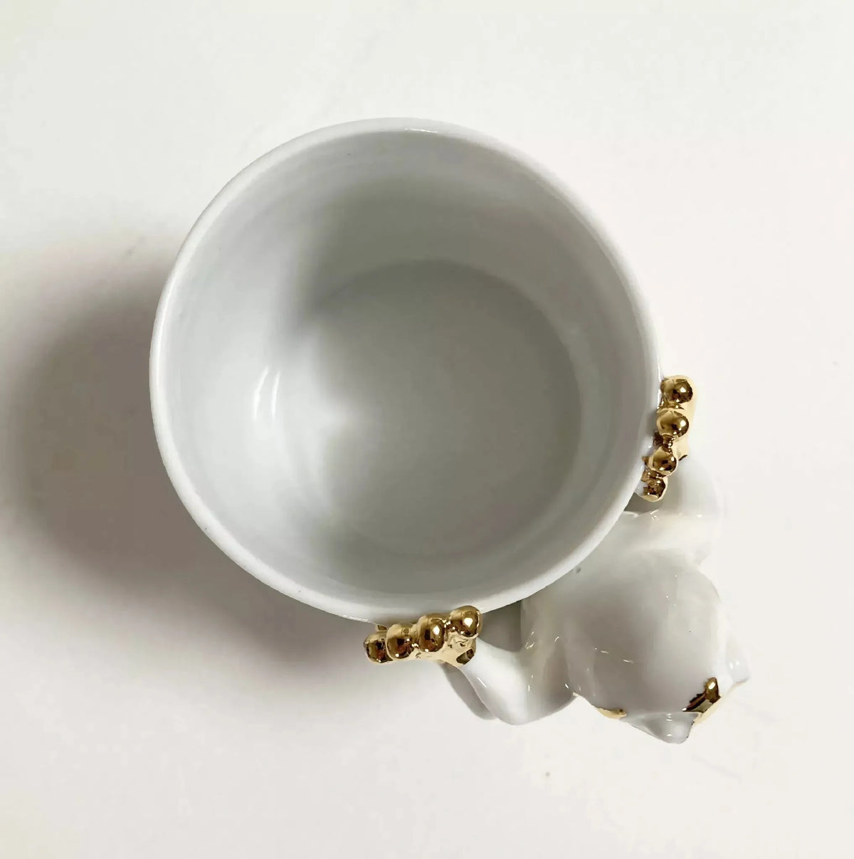 Tasse en céramique blanche vue du dessus, grenouille dorée près du bord