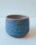 Tasse ronde en céramique bleue avec motifs décoratifs gravés sur le pourtour