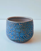 Tasse ronde en céramique bleue avec motifs décoratifs gravés sur le pourtour