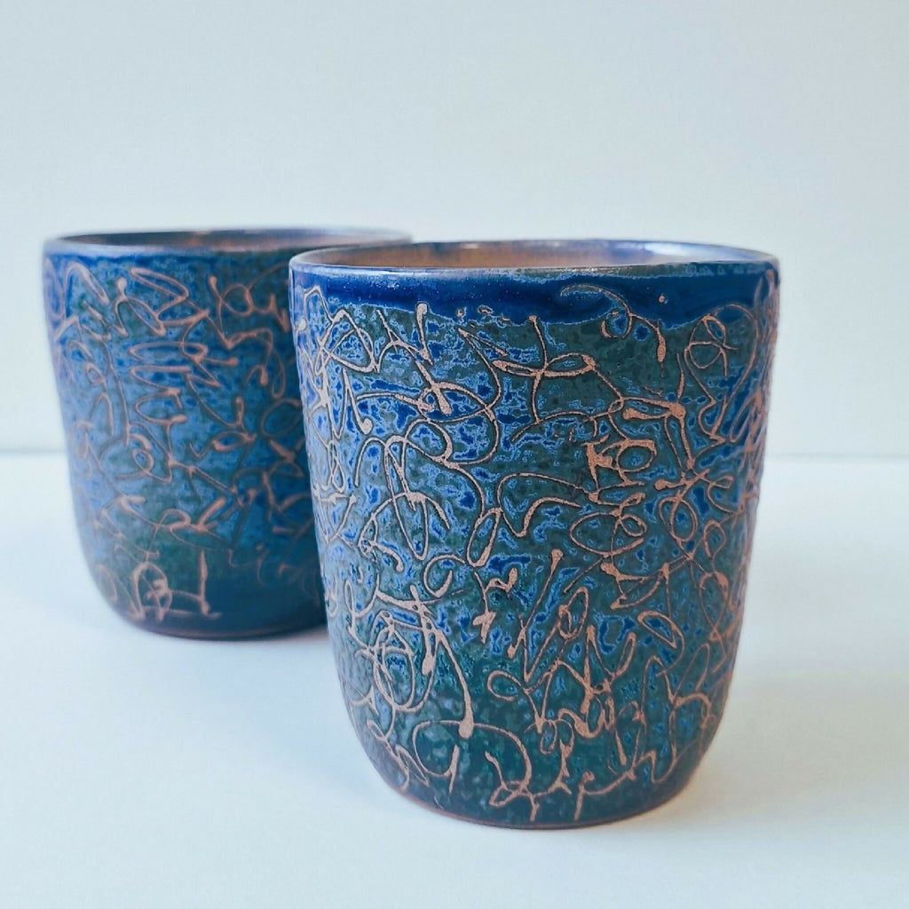 Deux tasses en céramique bleues, motifs entrelacés bleu et brun, vues de face