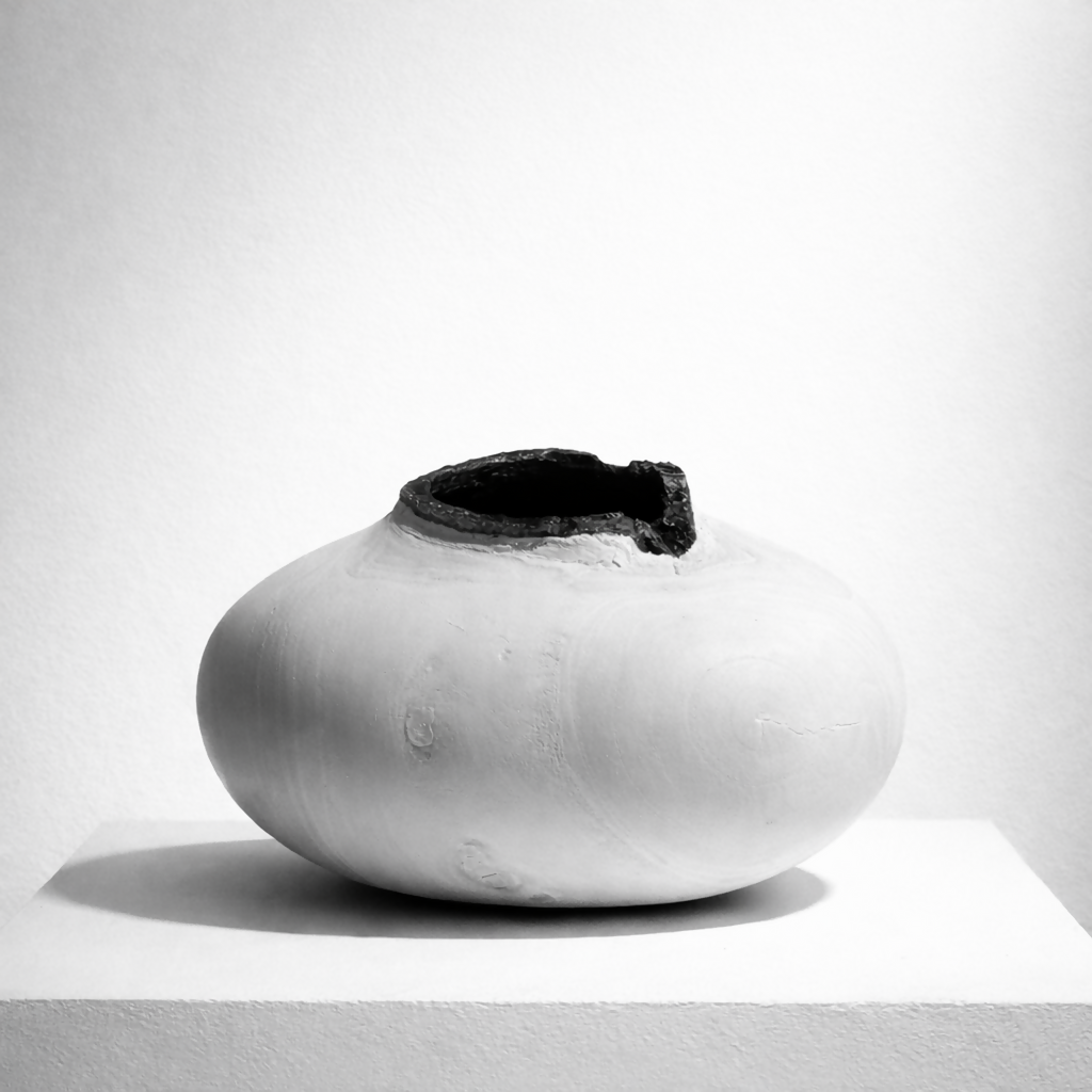 Vase céramique blanche ronde avec ouverture sombre au centre, silhouette épurée.