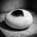 Vase céramique blanche au sommet évasé, ouverture noire bordée de matière brute.