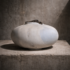 Vase céramique blanche ventrue avec ouverture sombre sur le haut, surface légèrement irrégulière.