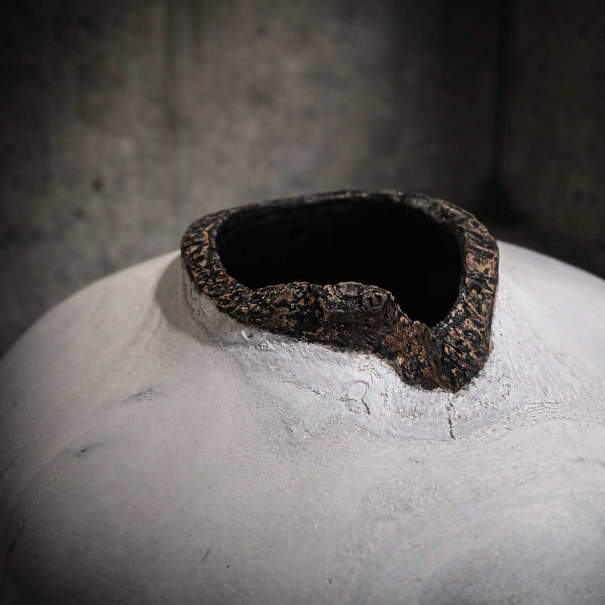 Vase céramique blanche : gros plan sur l’ouverture noire bordée de résidu brun.