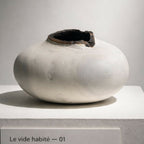 Vase céramique blanche à ouverture sombre, vue de face sur support.