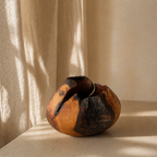 Bol décoratif en bois, teintes miel et orange, éclats noirs visibles sur l’ouverture.