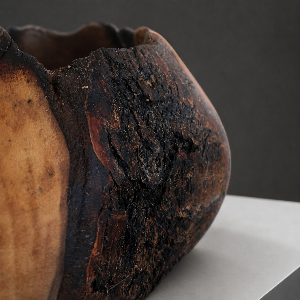 Bol décoratif en bois, gros plan sur texture noire et veinures brun-orange.