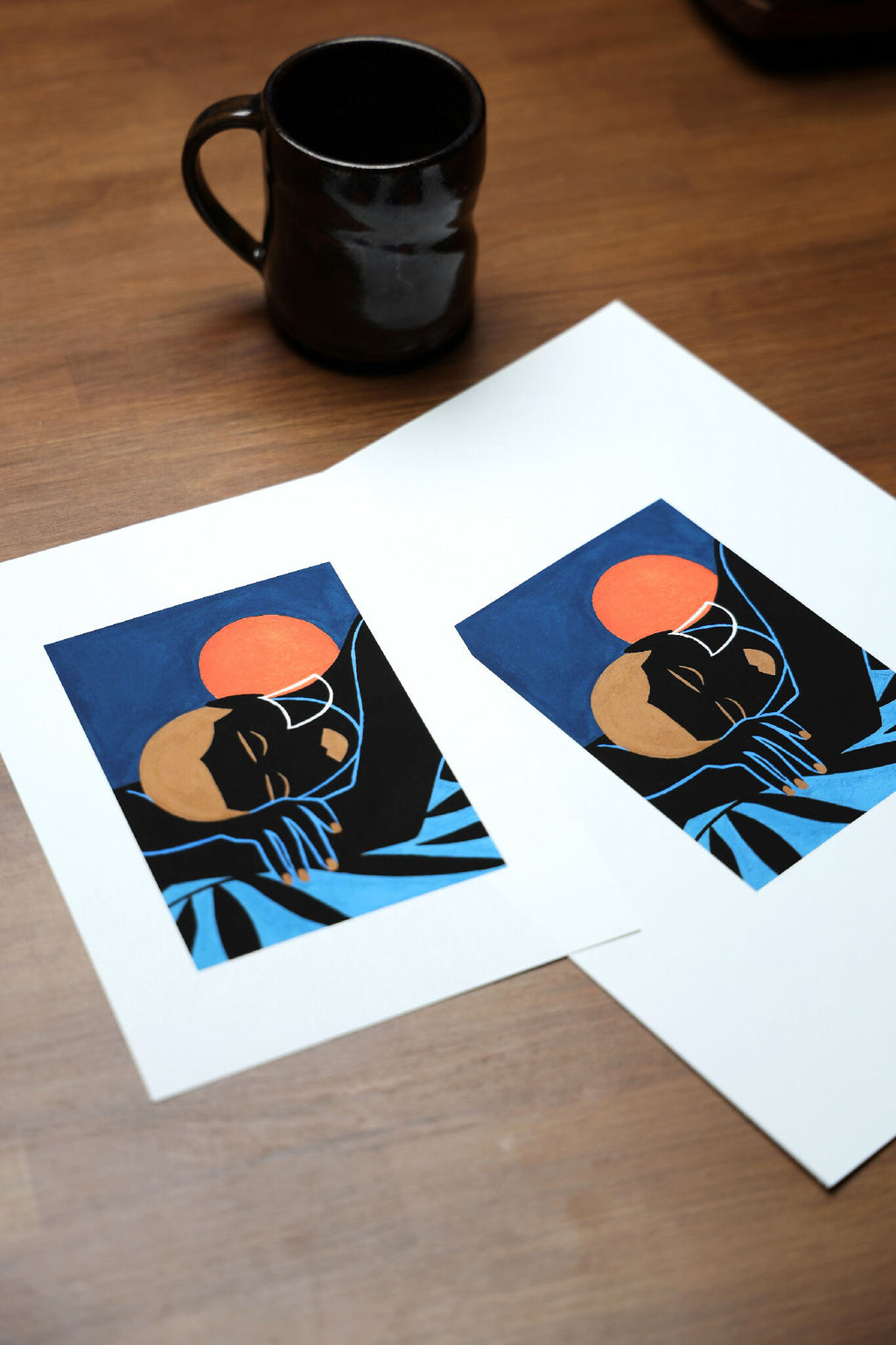 Deux tirages sur papier blanc : personnage noir, soleil orange et motif bleu