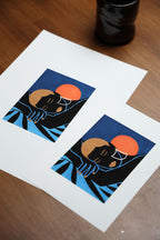 Deux cartes imprimées sur papier blanc avec personnage noir, soleil orange et fond bleu