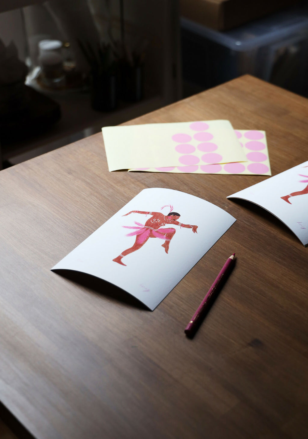 Tirage d’art Joséphine sur table : carte blanche avec ballerine rose et rouge, stylo.
