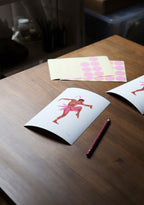 Tirage d’art Joséphine sur table : carte blanche avec ballerine rose et rouge, stylo.