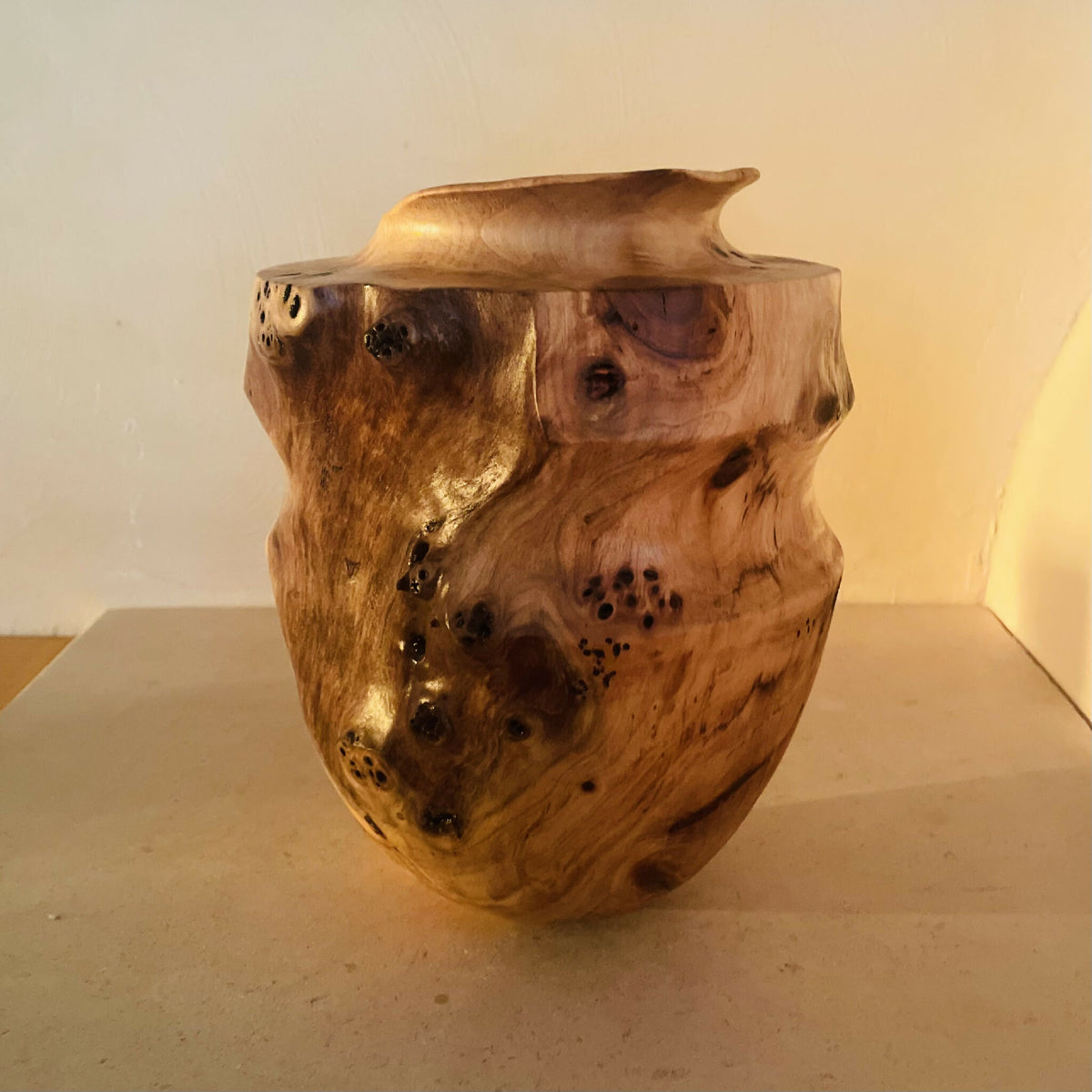 Vase en bois sculpté, vue de trois-quarts, ouverture ronde, bord évasé et taches.