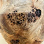 Détail du vase en bois sculpté : nœuds et trous noirs sur la surface.