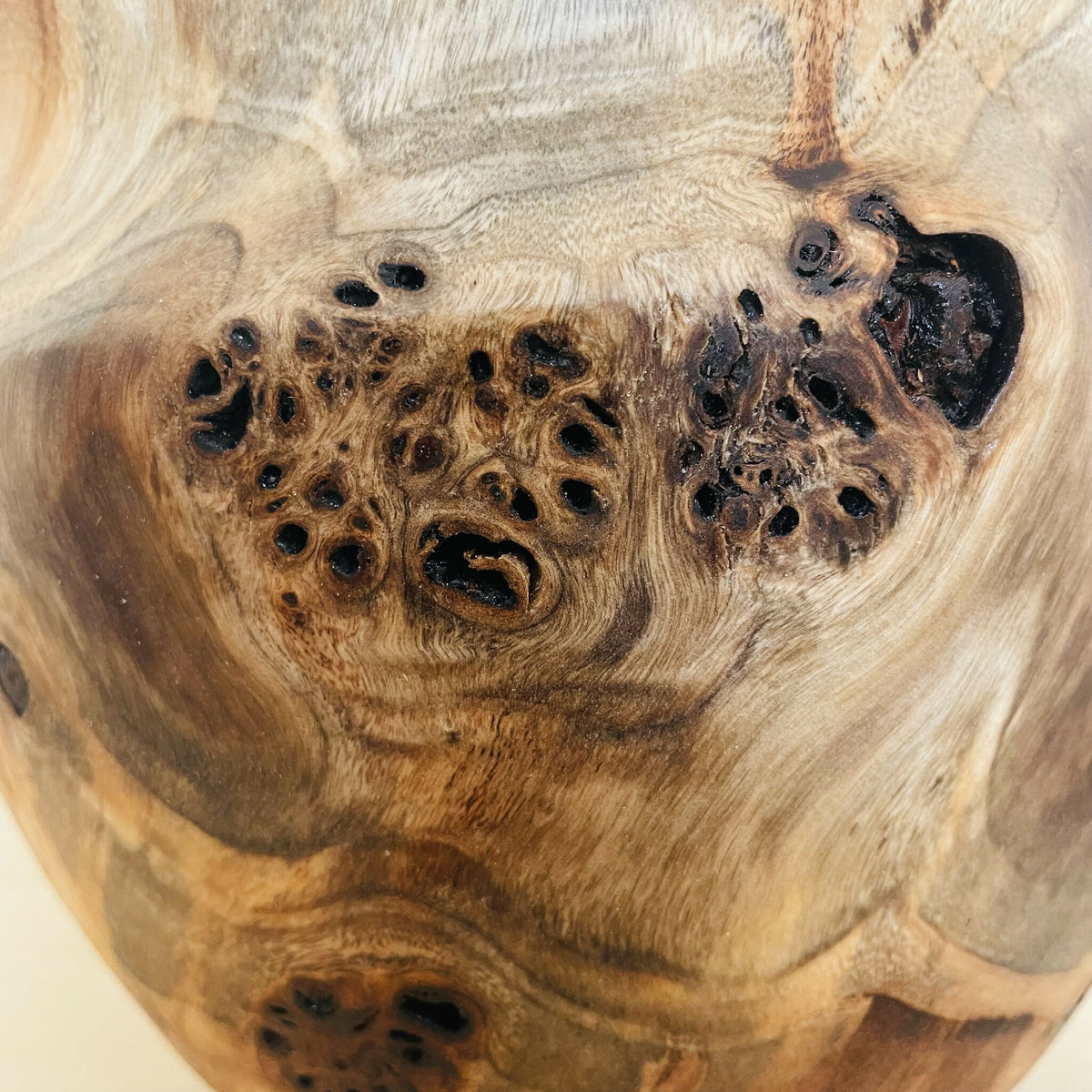 Détail du vase en bois sculpté : nœuds et trous noirs sur la surface.