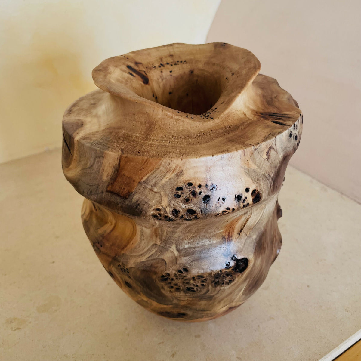 Vase en bois sculpté, ouverture circulaire et col évasé, motifs veineux et points noirs.