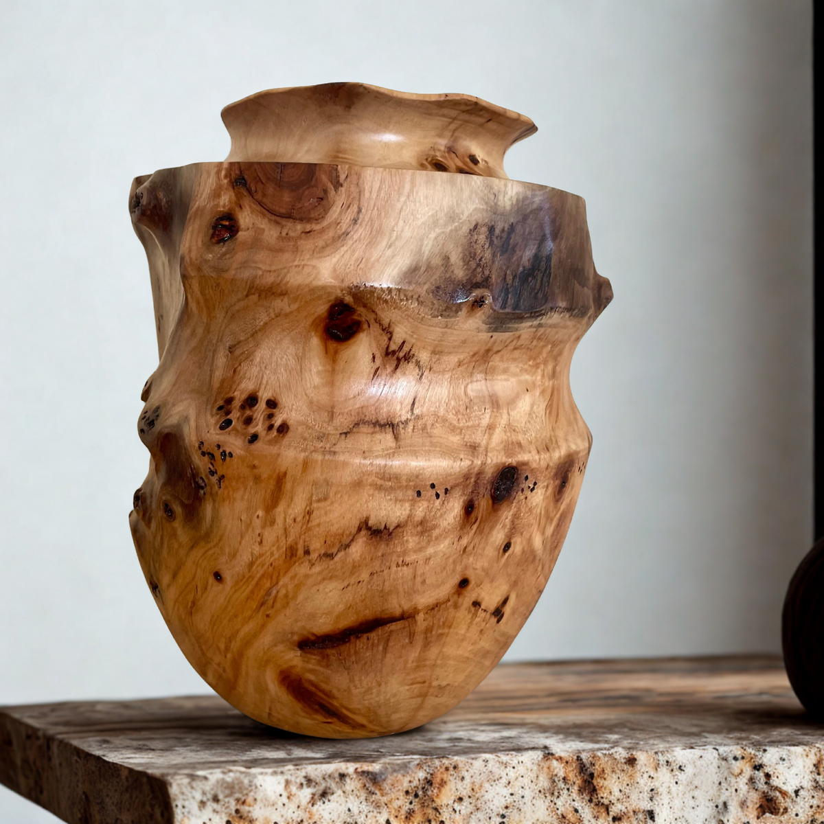Vase en bois sculpté, couleur miel clair, motifs sombres, vue de trois-quarts.