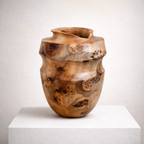 Vase en bois sculpté couleur miel, ouverture arrondie, surface mouchetée de noir.