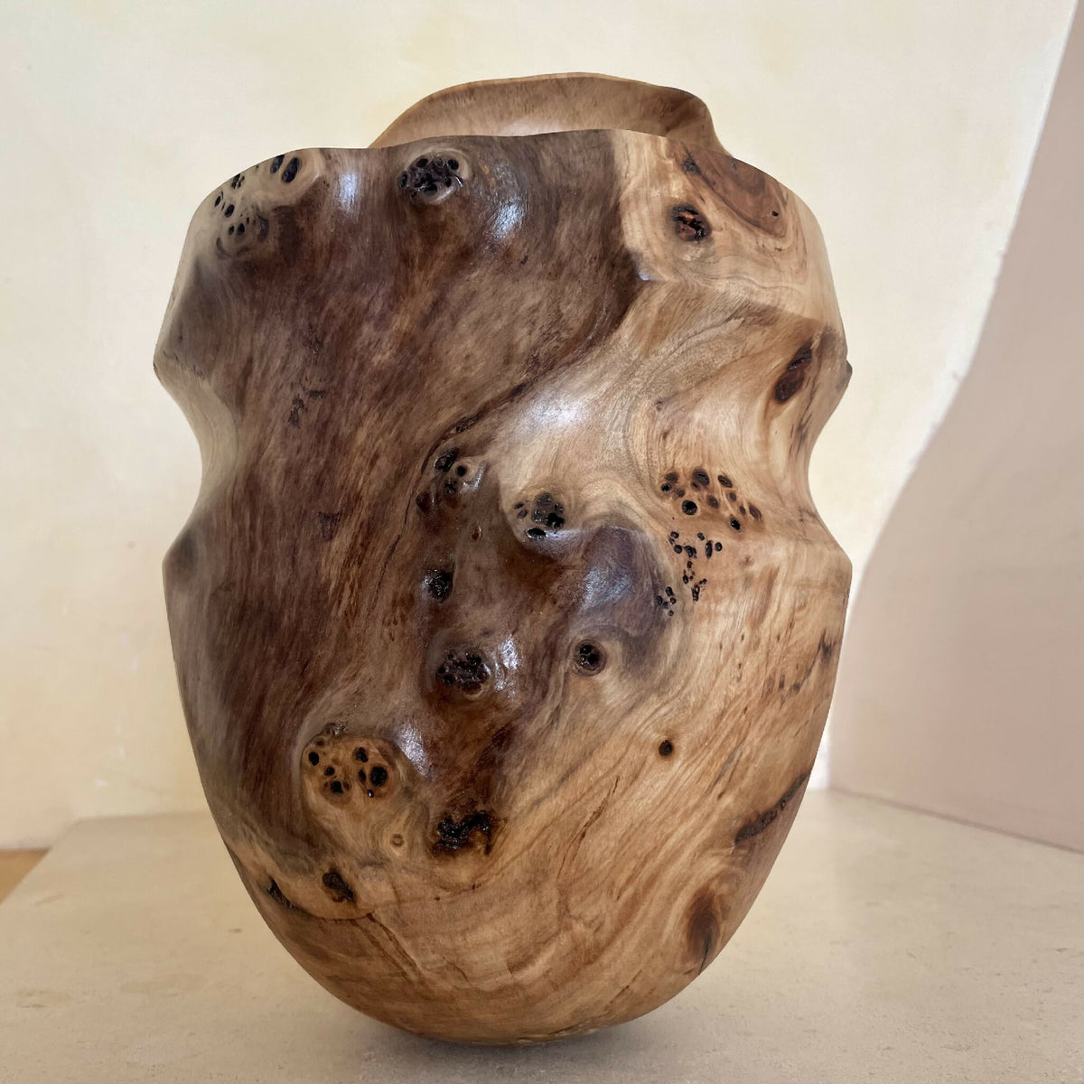Vase en bois sculpté couleur miel, motifs noirs et variations de grain, vue de face.