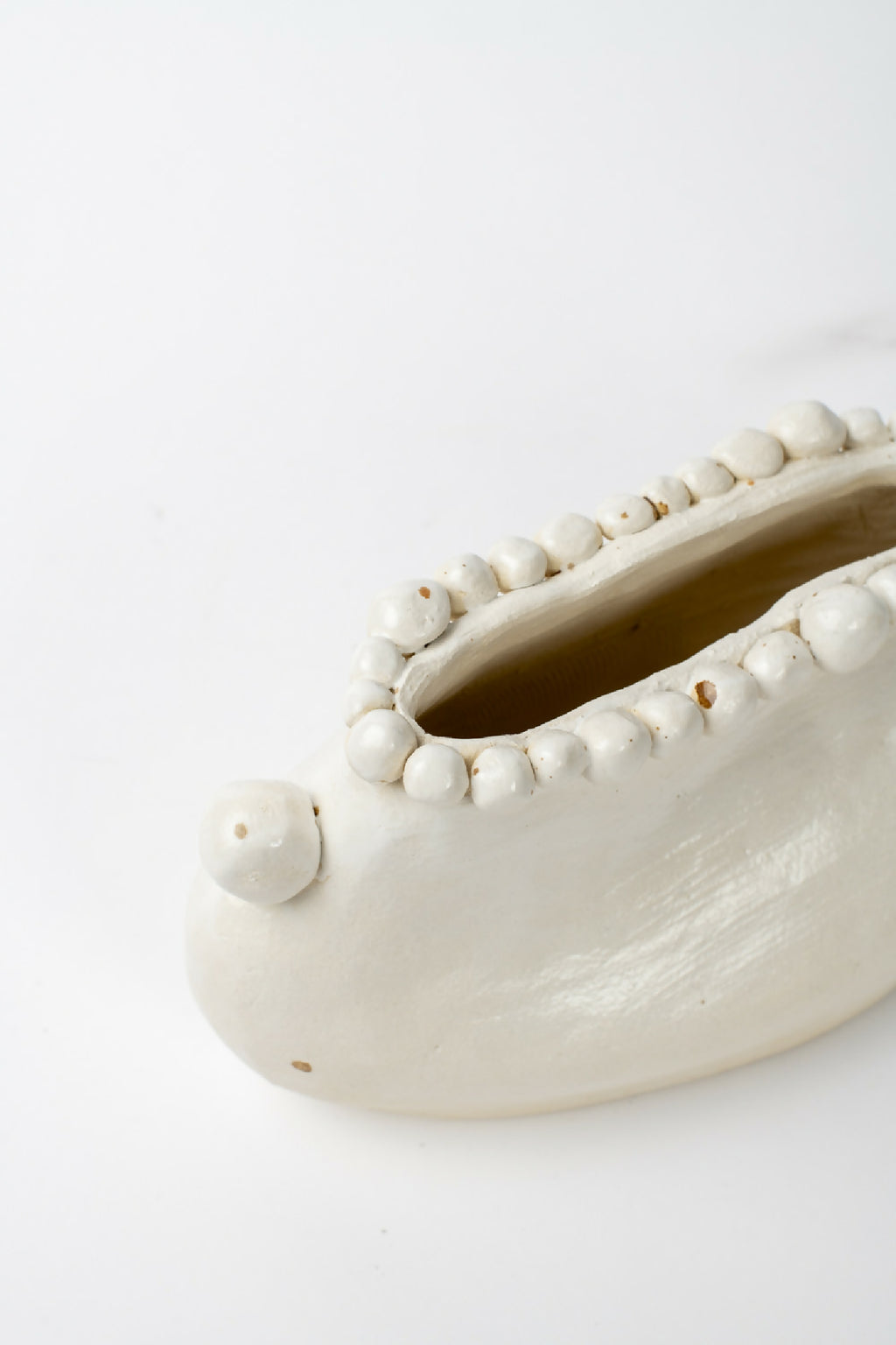 Vase en céramique blanche, gros plan de l’intérieur avec bord perlé et pointe latérale